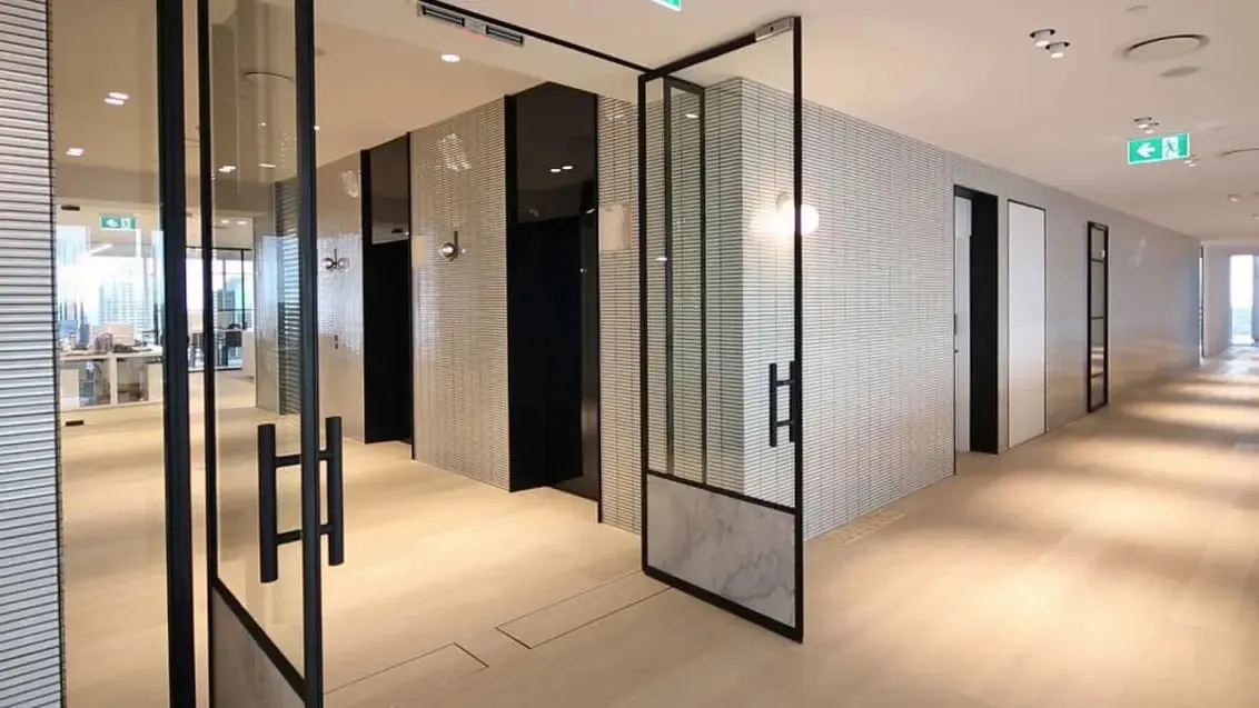 Puerta automática abatible doble con marco metálico negro.