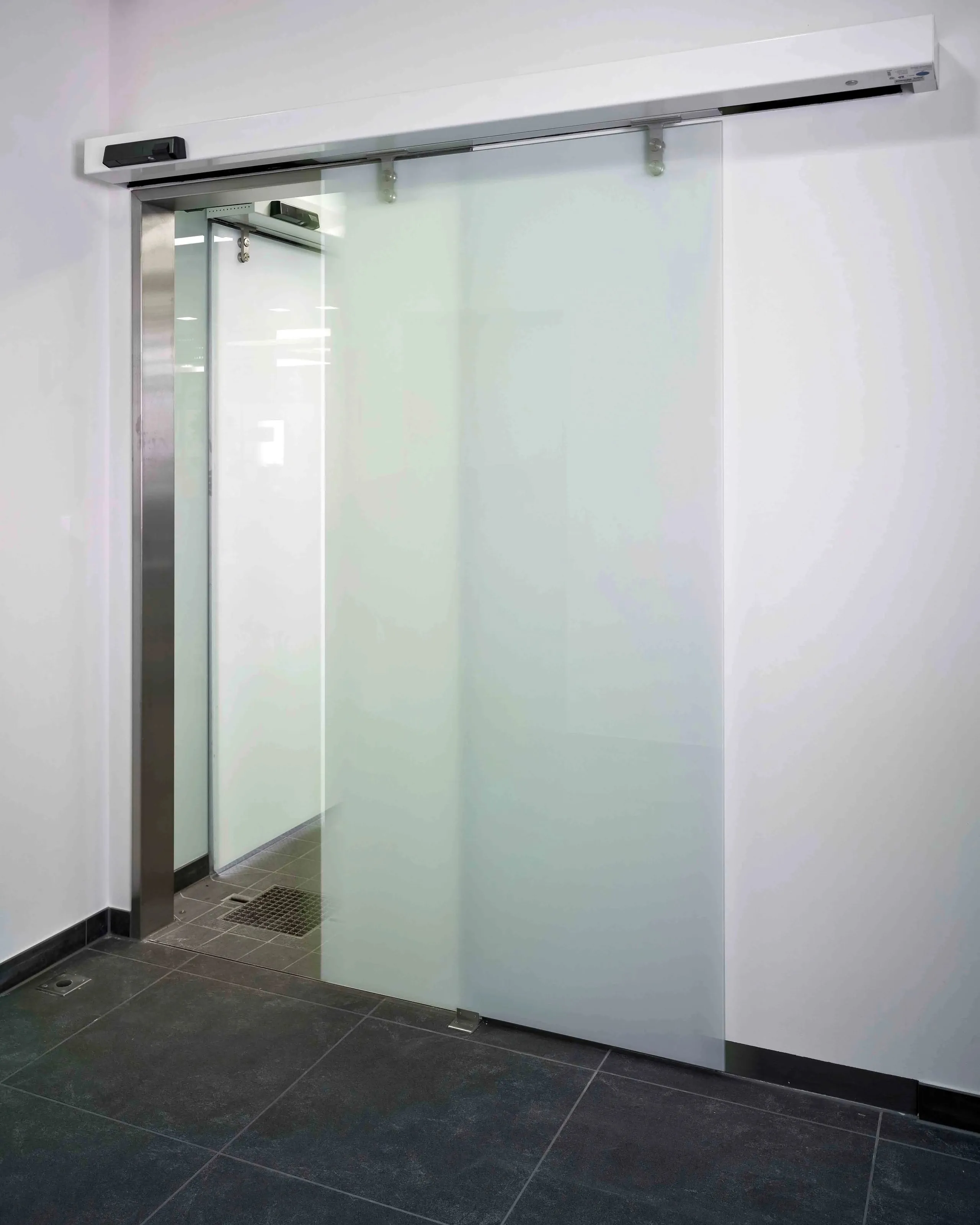 Puerta corrediza automática de cristal esmerilado.