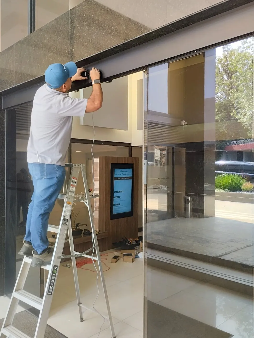 Técnico reparador trabajando en puertas automáticas.