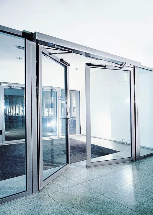 Puerta automática abatible con marco de aluminio y cristal claro.