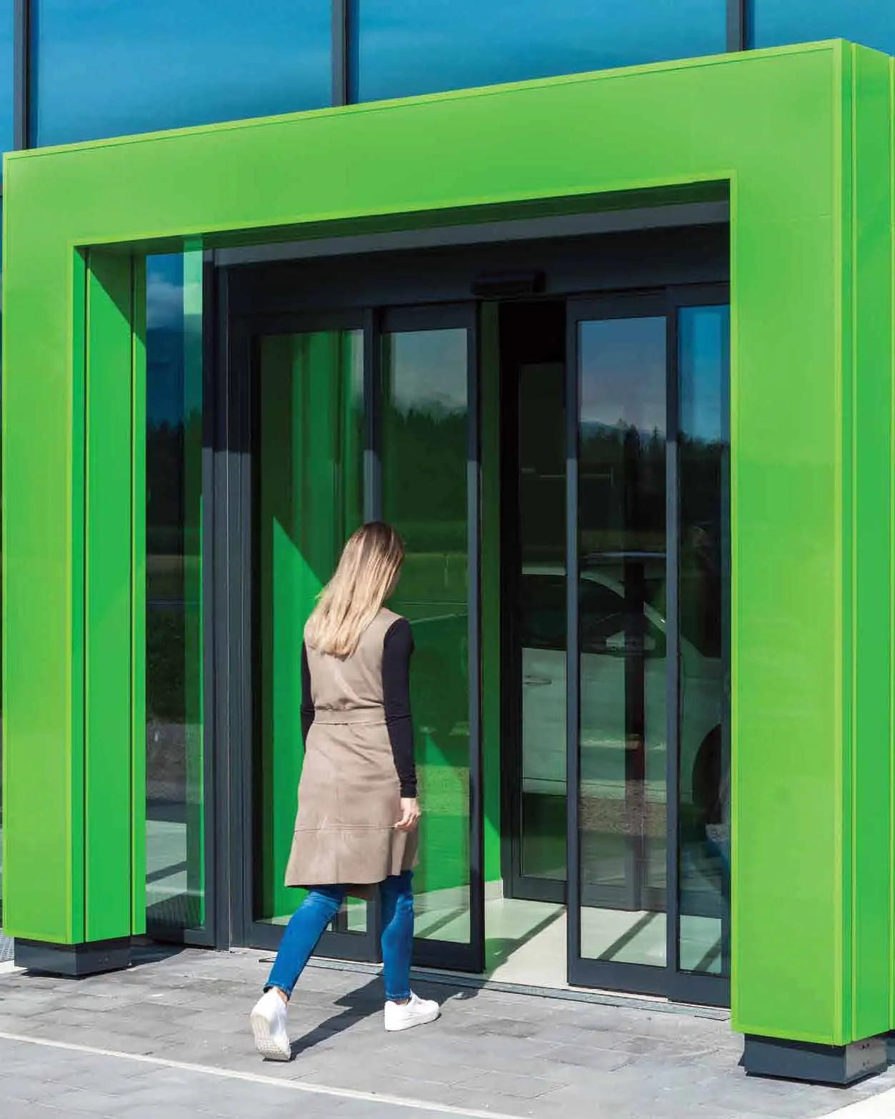 Puertas automáticas corredizas en exclusa con marco negro de aluminio.