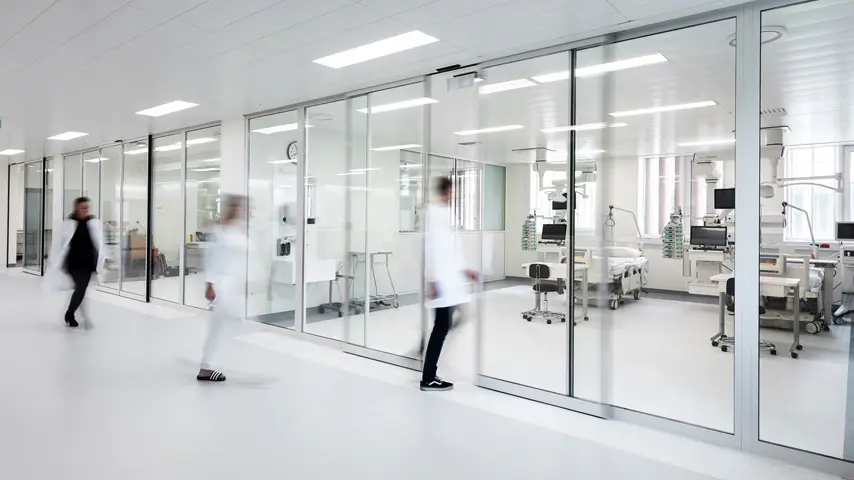 Puerta automática corrediza con marco blanco de aluminio y cristal claro.