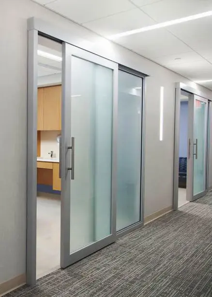 Puerta automática corrediza con marco  de aluminio y cristal esmerilado.